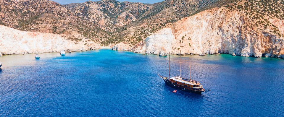 A small cruise ship anchored in a secluded cove with turquoise waters and rocky cliffs. A small cruise ship anchored in a secluded cove with turquoise waters and rocky cliffs.