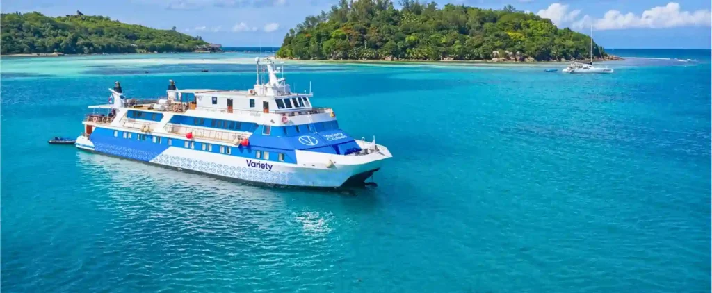 A small ship sailing through turquoise waters near a tropical island