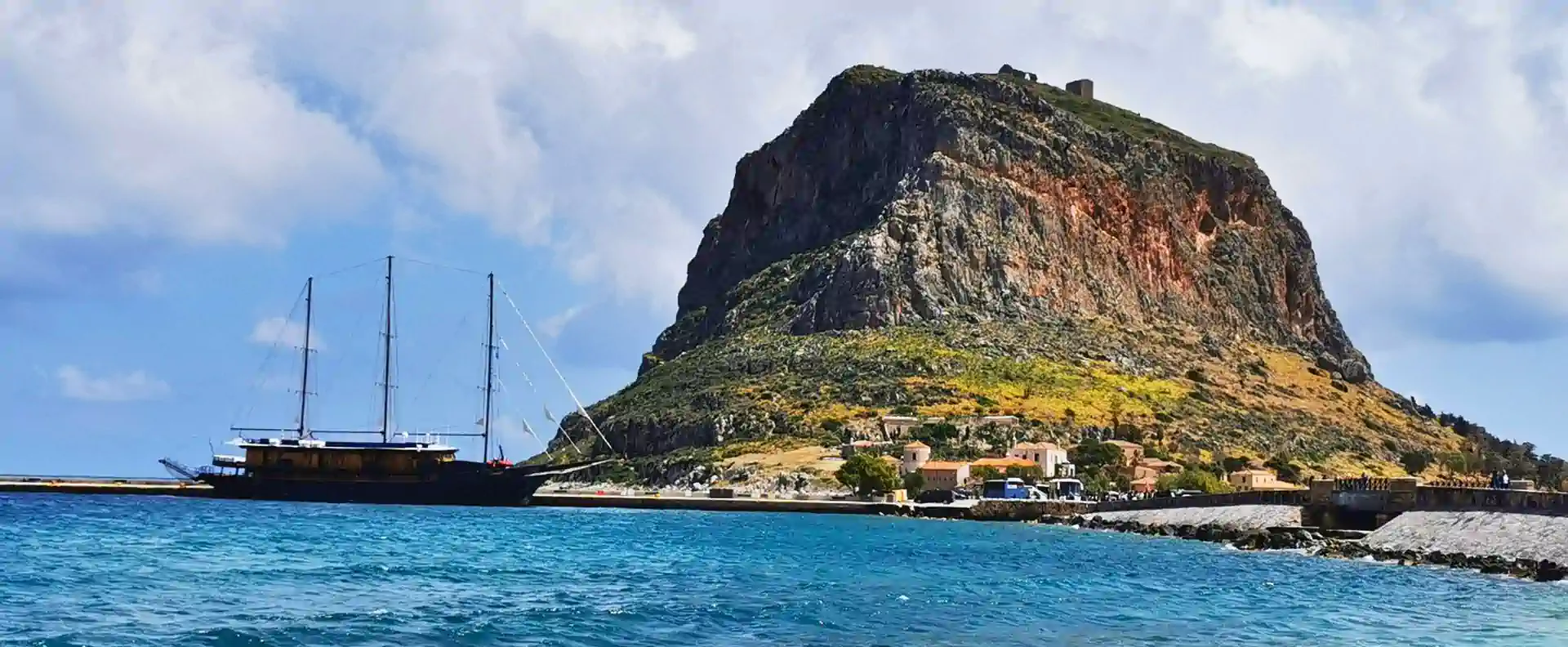 Galileo small ship moored below the dramatic rock of Monemvasia during the Athens to Cyclades Cruise