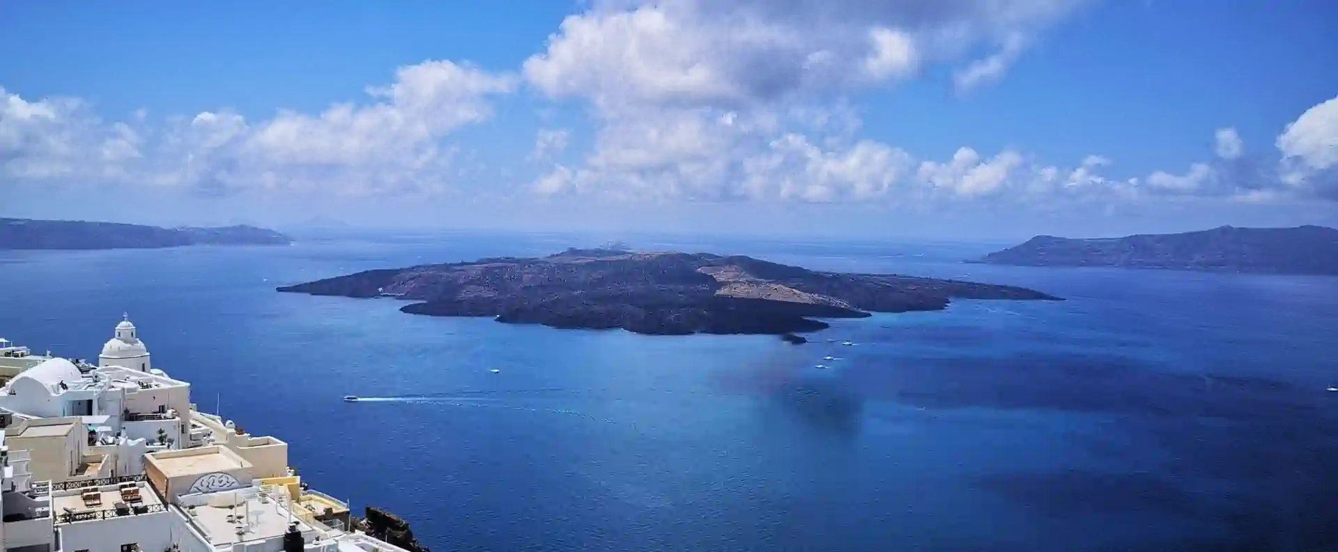 cyclades-cruise-itinerary-santorini-caldera-view.webp Cyclades cruise itinerary stop in Santorini with sweeping view of the volcanic caldera and whitewashed domes under blue skies.