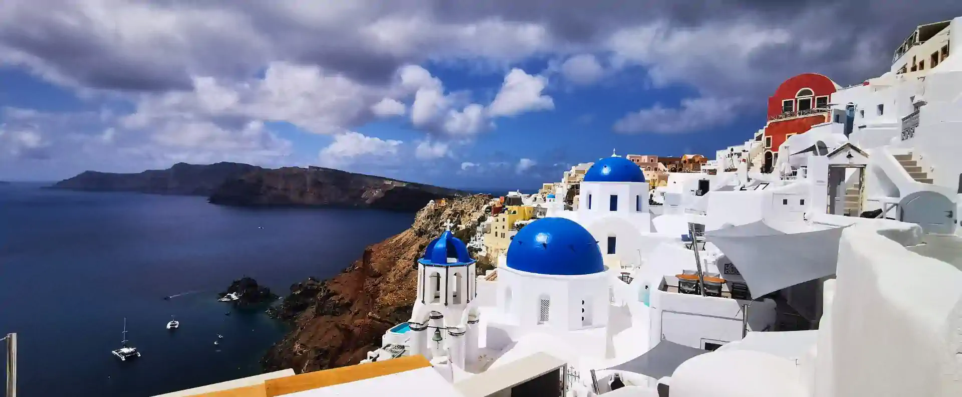 Iconic blue-domed churches of Oia overlooking the caldera, Santorini stop on the Athens to Cyclades Cruise.