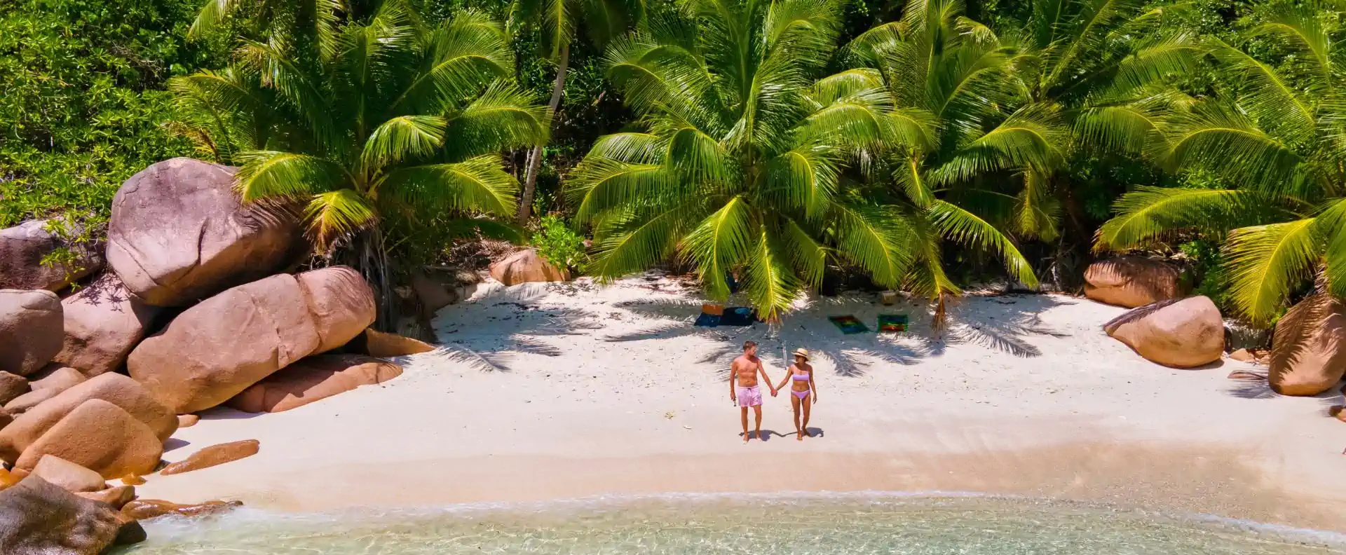 Couple on a palm-fringed cove during Seychelles island hopping, secluded beach on La Digue.
