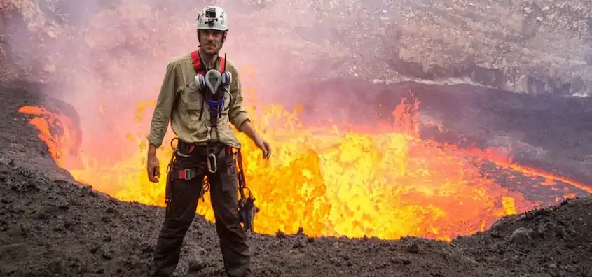 Aeolian Islands Cruise host George Kourounis standing near an active lava flow, wearing safety gear.