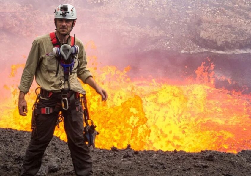 Aeolian Islands Cruise host George Kourounis standing near an active lava flow, wearing safety gear.